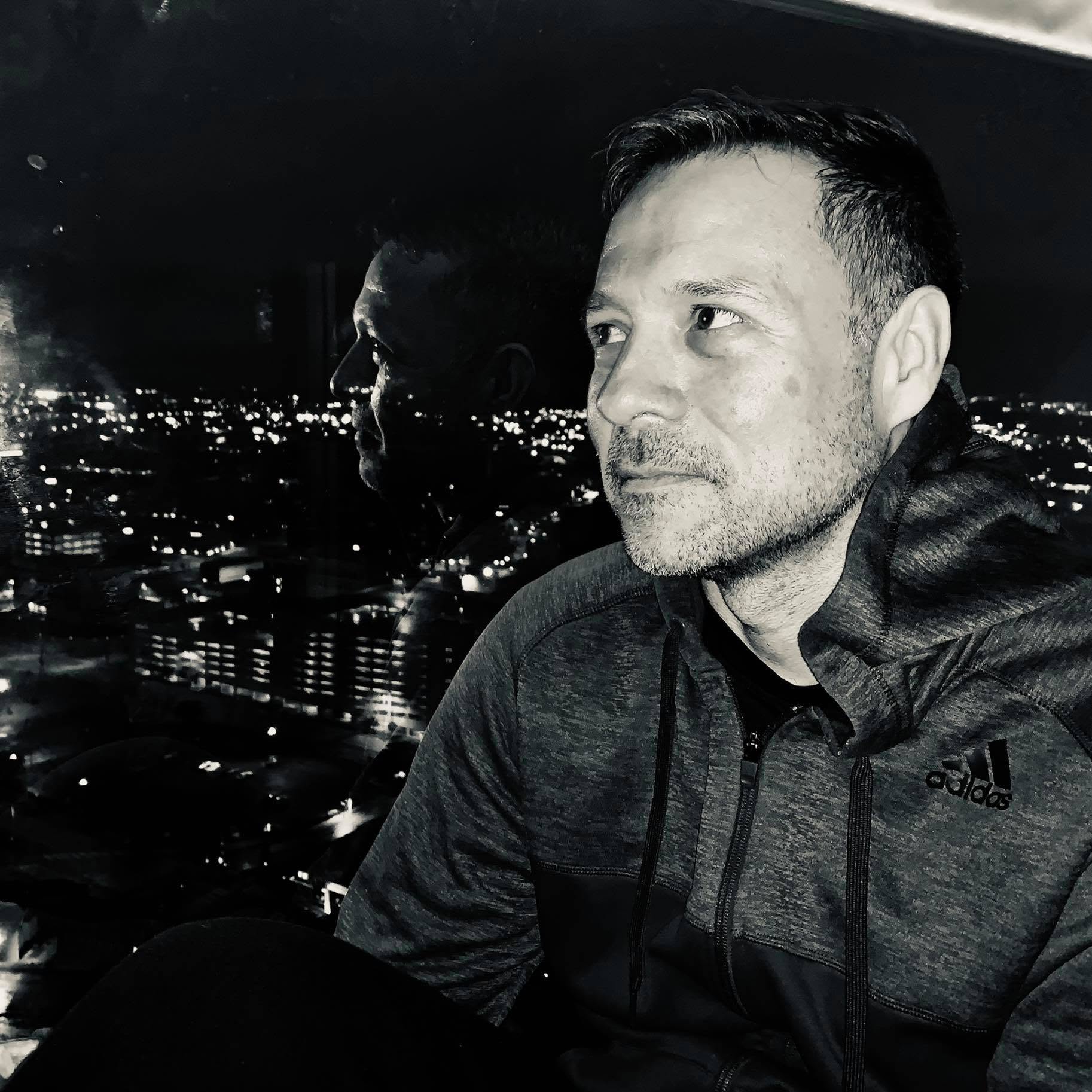 Joe Bannon seated by a window overlooking city lights at night